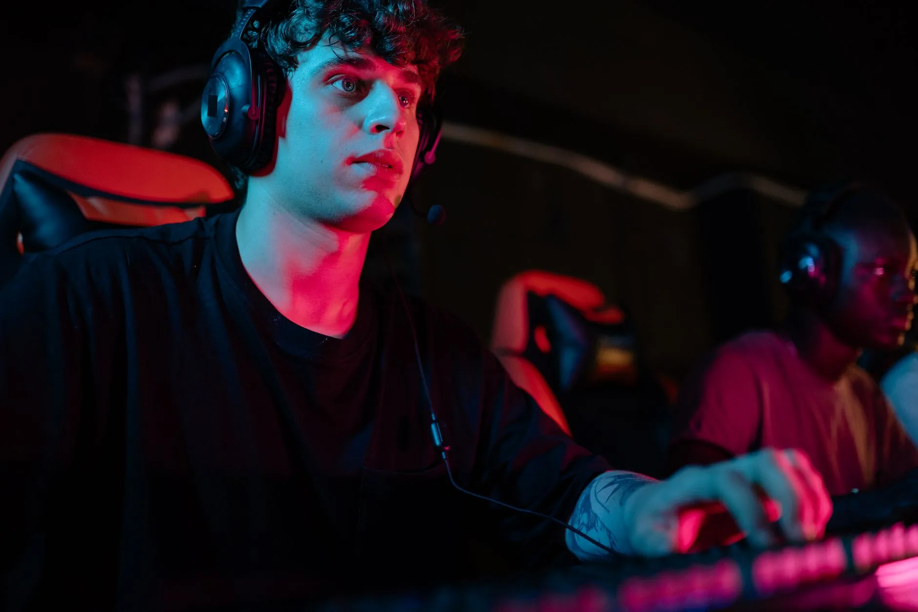 Focused young man gaming with headset at PC gaming setup, showcasing intense concentration.